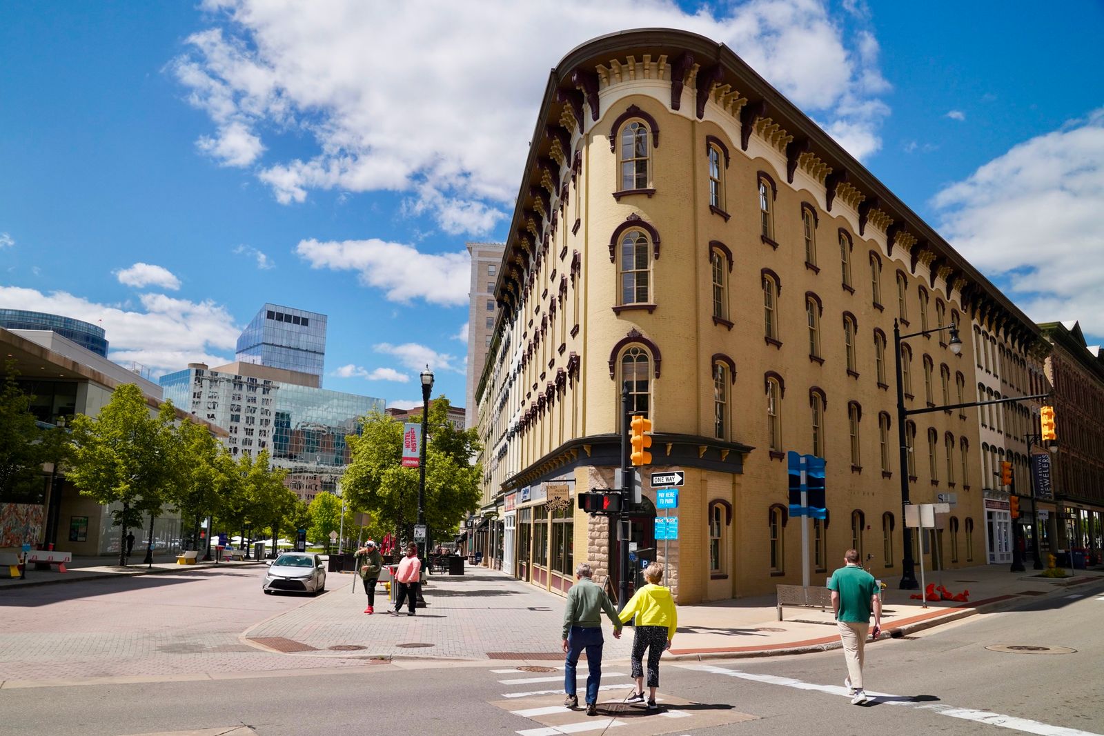 A historic yellow brick building on a downtown Grand Rapids corner, people crossing the street