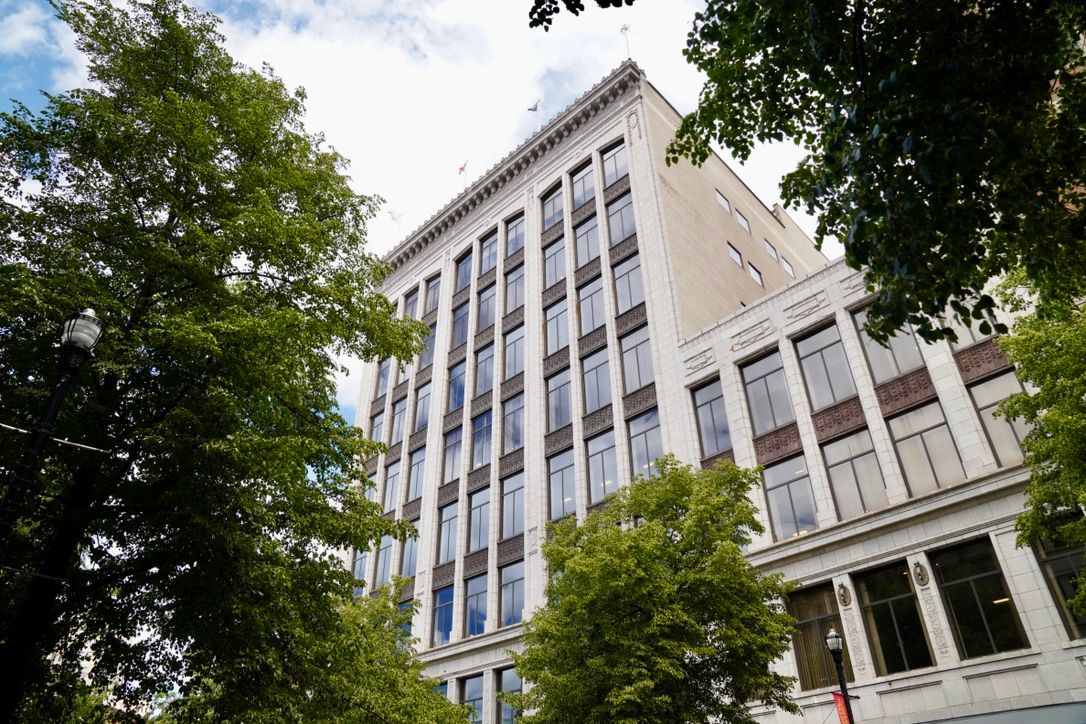 A white historic office building framed by trees